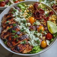 Healthy Chicken and Street Corn Bowls feature juicy grilled chicken thighs, charred sweet corn, and crisp romaine in a vibrant bowl, drizzled with tangy Greek yogurt dressing.