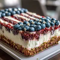 Festive no-bake cheesecake decorated with fresh blueberries and strawberries to resemble the American flag for Fourth of July.